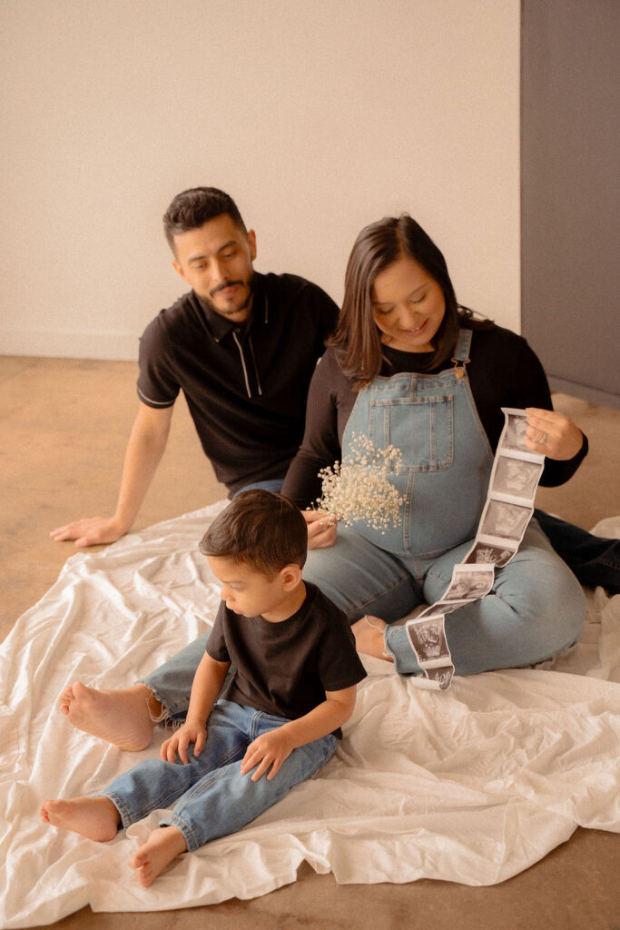 Family holding sonogram at their studio maternity photoshoot