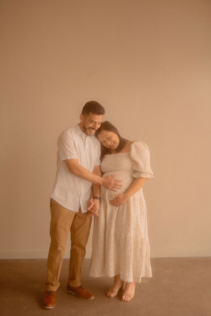 Pregnant couple leaned against each other embracing their unborn child 