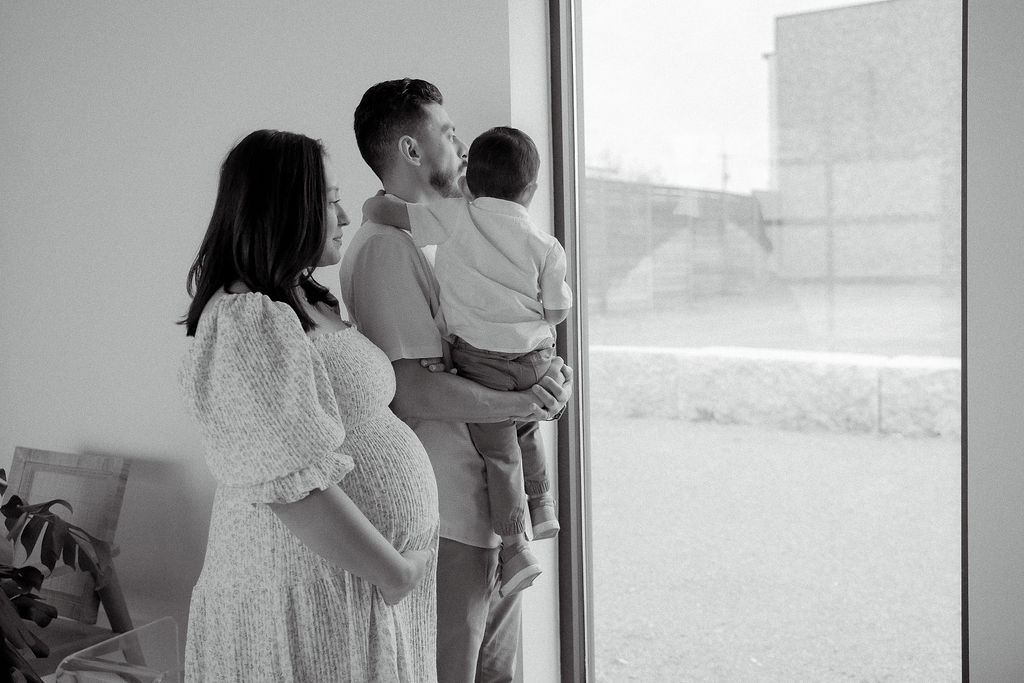 Mom and dad looking out of the window with their son inside a studio