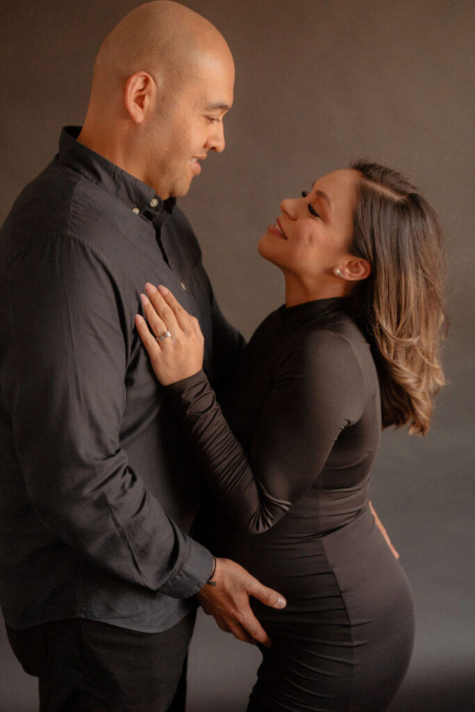 Pregnant couple starring deeply in each others eyes at a studio