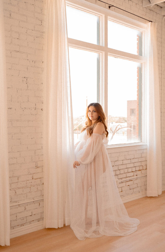Boho maternity dress near a white brick wall