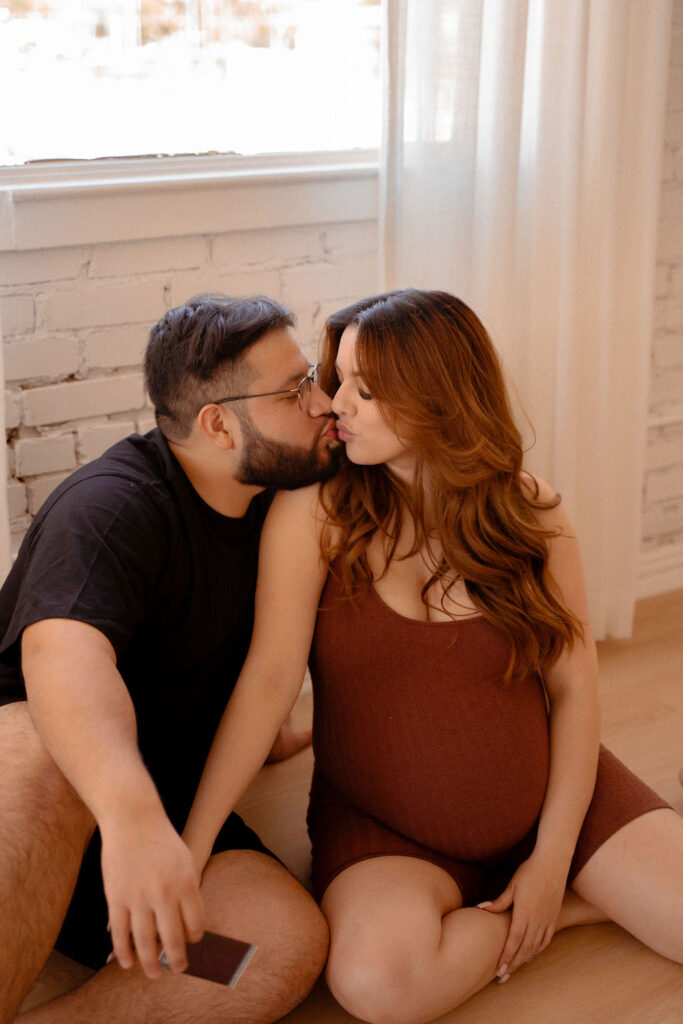 Pregnant couple kissing on the floor