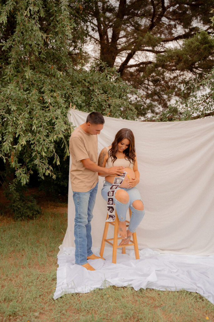 Mom and dad looking down at pregnant belly while holding sonogram