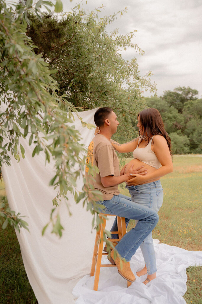 Pregnant couple gazing at each other under a serene tree