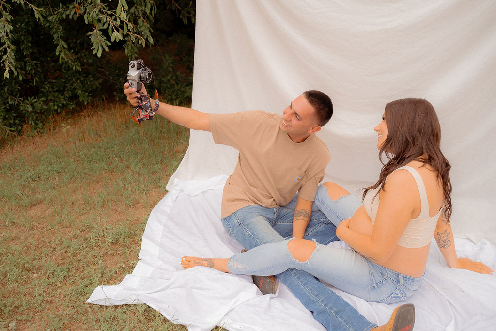 Dad taking photos of pregnant mom with a vintage film camera at a fun maternity photoshoot 